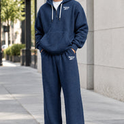 A man wearing a navy blue Reebok waffle-knit lounge set, featuring a pullover hoodie with a half-zip front and matching sweatpants,
