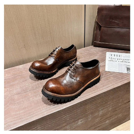 Pair of brown leather shoes on a wooden surface with a newspaper in the background.