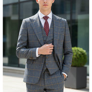 Gray checkered suit on a mannequin with a red tie against a beige curtain background