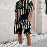 A person wearing a matching short-sleeve t-shirt and shorts set with an American flag and deer silhouette print, standing outdoors against a stone wall.
