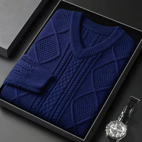 Blue textured sweater in a black box with a silver watch on a dark surface