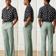 A three-view model photo showing a man wearing sage green wide-leg trousers and a navy short-sleeve button-up shirt with white polka dots, standing against a white paneled wall.