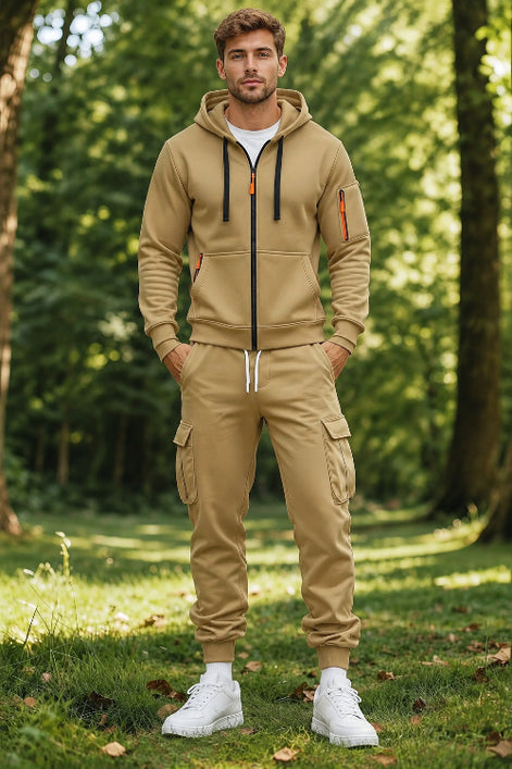 A man wearing a matching tan zip-up hoodie and jogger pants set with white sneakers,