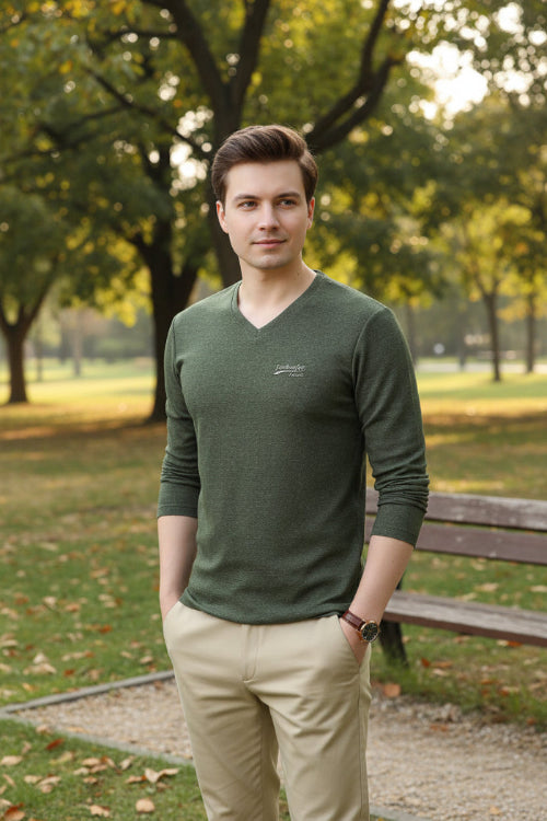 Person wearing a green long-sleeve shirt with a logo on a gray background