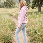 A pink pullover hoodie shown on a model from both the front and back. The front features the text 'Jesus IS THE LIGHT' in black, blue, and gold.