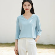 Woman wearing a light blue V-neck shirt with a blurred background