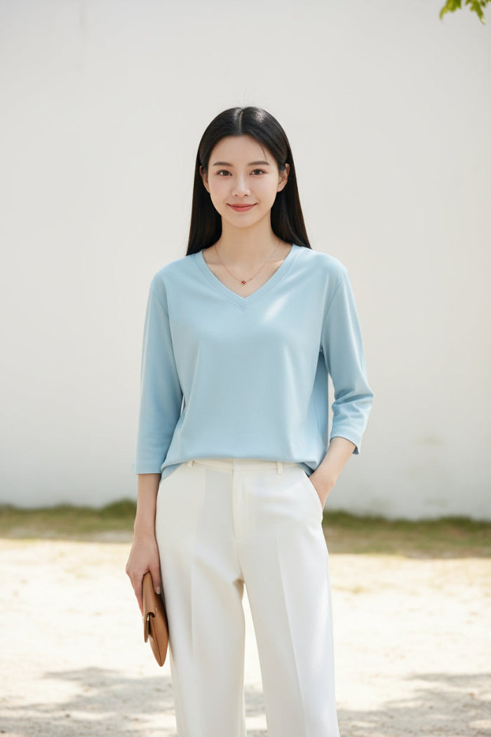 Woman wearing a light blue V-neck shirt with a blurred background