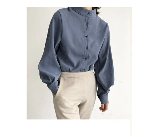 Person wearing a blue blouse with long sleeves and beige pants on a white background