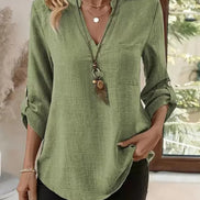 Green shirt worn by a person with a decorative pendant, indoors.