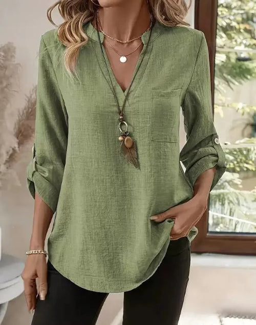Green shirt worn by a person with a decorative pendant, indoors.