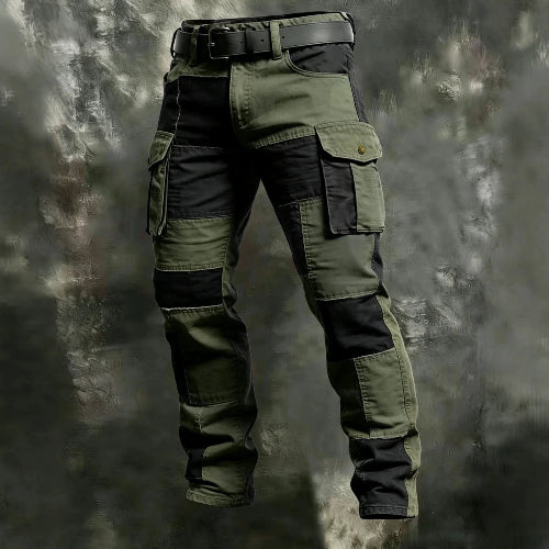 Olive green and black color-block cargo pants with flap thigh pockets and a black belt against a textured gray background.