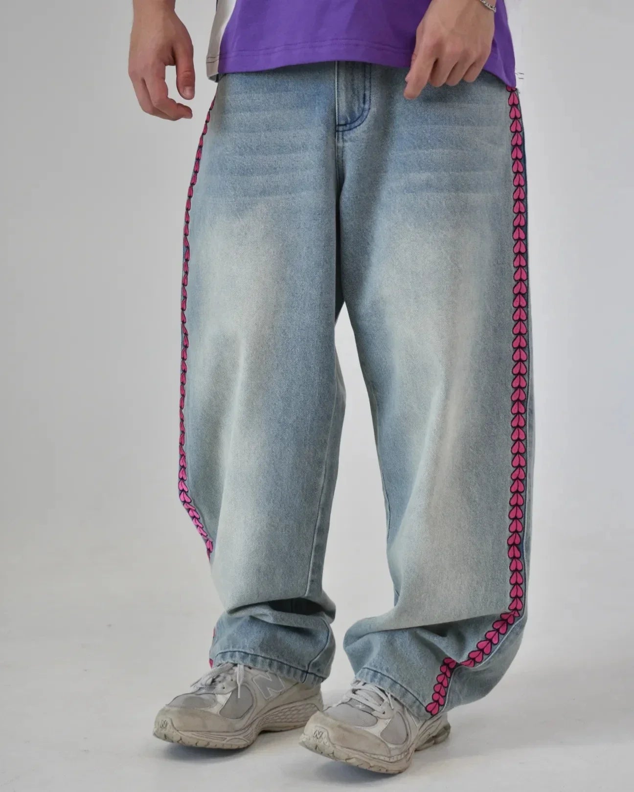 Light blue jeans with pink stitching worn by a person on a plain background