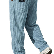 Light blue striped corduroy pants shown from the back on a model, featuring a black brand patch on the back pocket and white low-top sneakers.