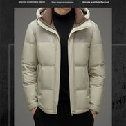 A men's casual puffer jacket in light beige/cream with a brown hood lining, worn by a model over a black turtleneck. The image includes marketing text at the top and bottom on a dark textured background.