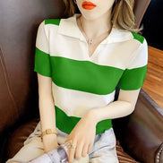 A woman wearing a short-sleeve knit polo shirt with bold green and white horizontal stripes, seated on a brown leather chair.
