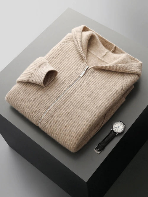 Folded beige sweater with a watch on a gray surface