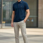 Navy blue polo shirt with white trim on a hanger against a gray background