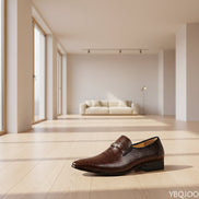 Brown leather dress shoe with crocodile pattern on a wooden surface with blurred background