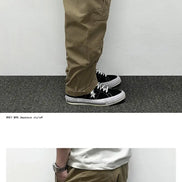 Side and rear-angle views of a model wearing khaki cargo pants, showing large flap thigh pockets, back pockets, and stitched knee panels.
