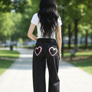 Person wearing black jeans with a heart design on a white background