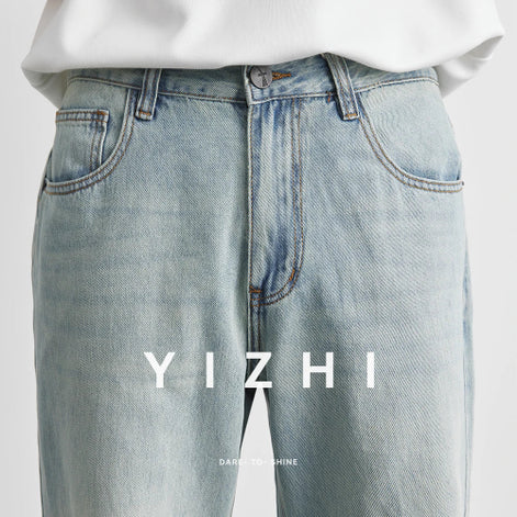 Light blue jeans with a white shirt on a light gray background, featuring the brand 'YIZHI'.