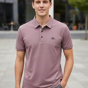 Purple polo shirt on a hanger with a hand touching it, brand logo visible