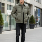An olive green men's puffer jacket with a ribbed corduroy collar, shown open to reveal a dark gray inner lining. The jacket is displayed against a neutral gray background with a promotional badge on the left highlighting its duck down technology, and the brand name 'LANGBEEYAR' is visible in the top left corner.