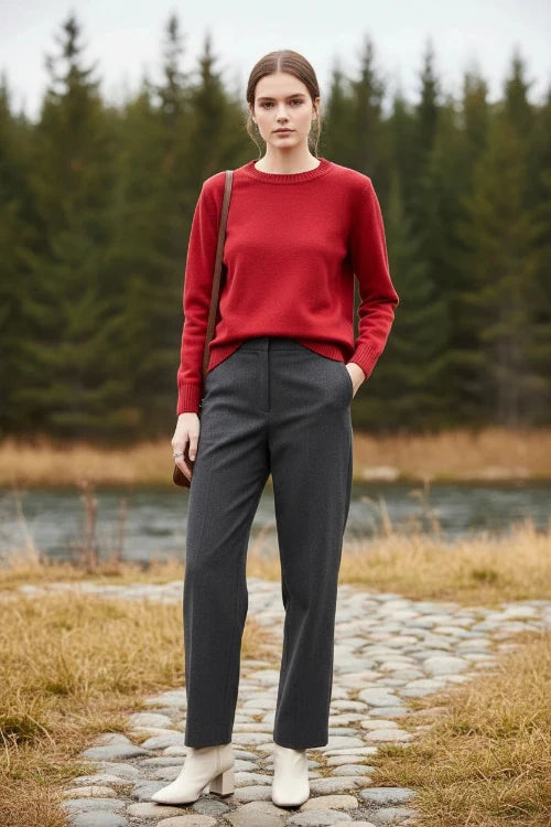 A woman wearing a bright red long-sleeve crewneck knit sweater, black sunglasses, and gold earrings, holding a brown shoulder bag strap.