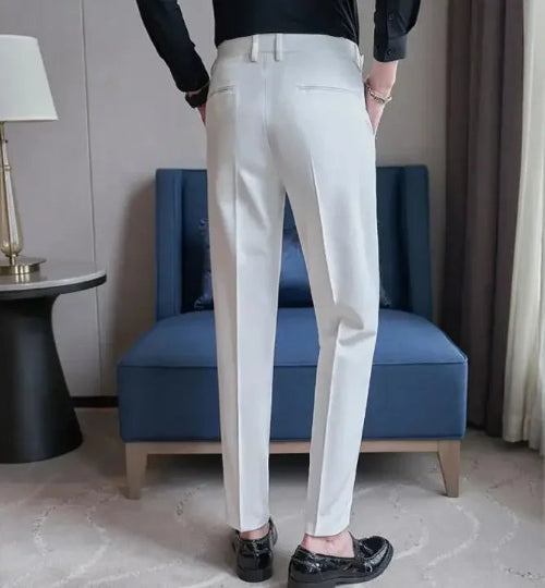 Person wearing white pants standing in a room with a blue chair and lamp.