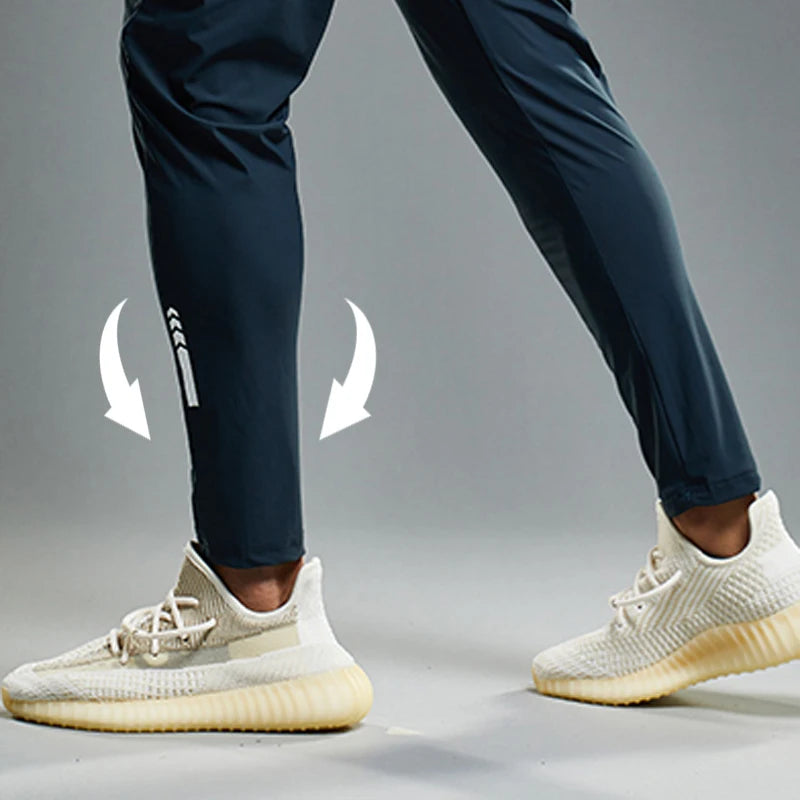 White sneakers with a brand logo on navy pants against a gray background