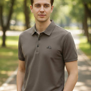 Brown polo shirt on a hanger with a hand touching the fabric