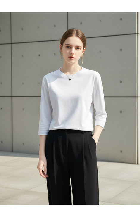 Person wearing a white long-sleeve shirt and black pants against a neutral background