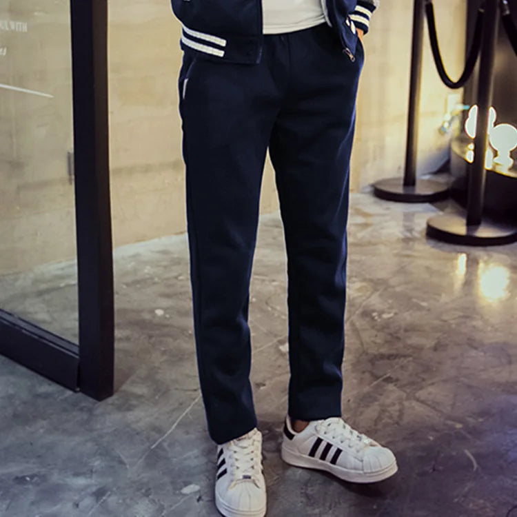 Person wearing navy pants and white sneakers with black stripes indoors.