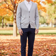 Gray cardigan over a white shirt on a wooden hanger against a dark background