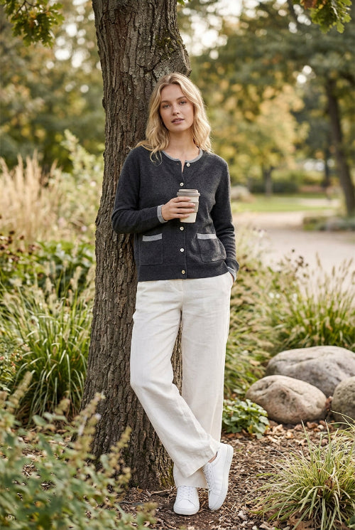 A folded dark gray knit cardigan sweater with contrasting light gray ribbed trim on the collar and sleeve cuff, featuring two light-colored buttons, 