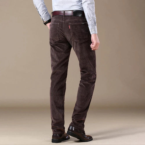 Brown corduroy pants worn by a person on a beige background