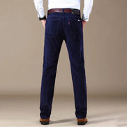 Navy blue corduroy pants worn by a person on a beige background