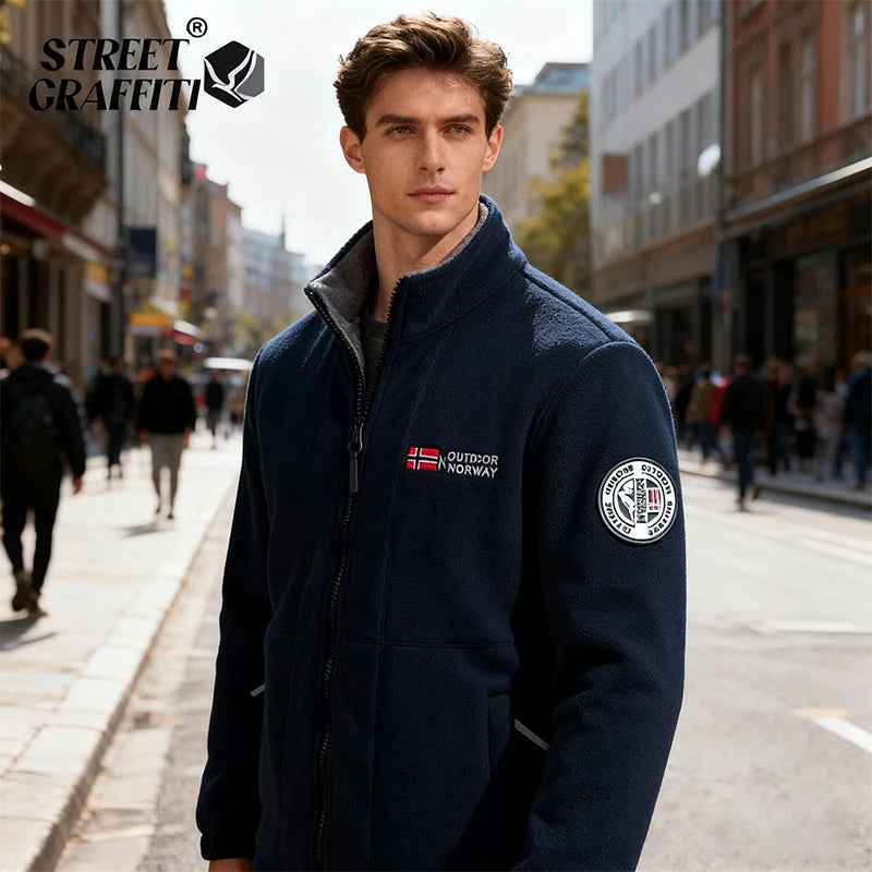 Man wearing a navy jacket with brand logos on a city street