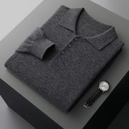 Folded gray sweater on a dark surface with a watch beside it