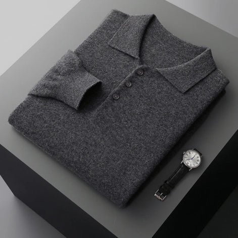 Folded gray sweater on a dark surface with a watch beside it