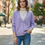 A person wearing a soft lavender cardigan over a cream turtleneck sweater, 