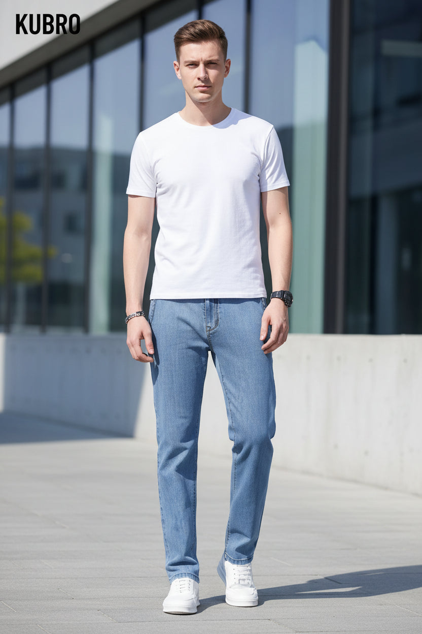 Person wearing light blue jeans and white sneakers on a blurred background with 'KUBRO' branding.