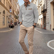 Man wearing a gray long-sleeve polo shirt with plaid accents on a city street.