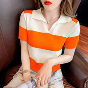 A woman wearing a short-sleeve knit polo shirt with bold horizontal orange and off-white stripes, seated on a dark brown leather chair.