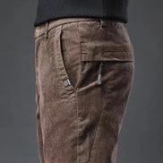 Brown corduroy pants with zippers on a dark gray background