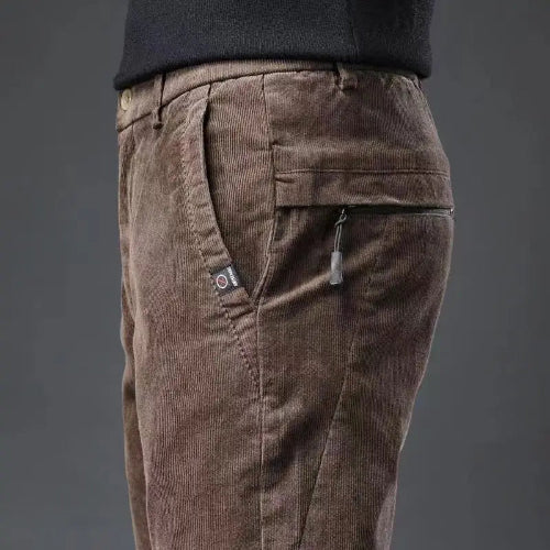 Brown corduroy pants with zippers on a dark gray background