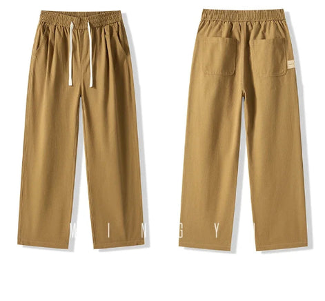 Front and back views of khaki straight-leg pants laid flat, showing an elastic waistband, white drawstring, slanted side pockets, and two back patch pockets.⠋
