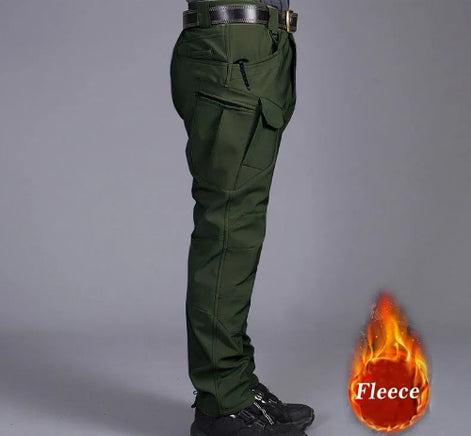 Side view of a model wearing dark olive green cargo pants with a zippered thigh pocket, flap pocket, black belt, and black shoes, alongside a fleece label graphic against a gray background.