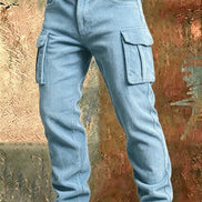 Light blue corduroy cargo pants with flap thigh pockets and a brown belt against a textured rust-colored metal background.