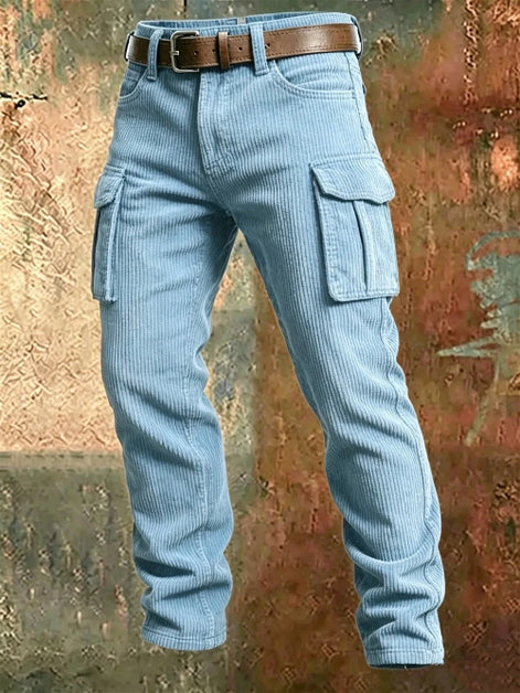 Light blue corduroy cargo pants with flap thigh pockets and a brown belt against a textured rust-colored metal background.